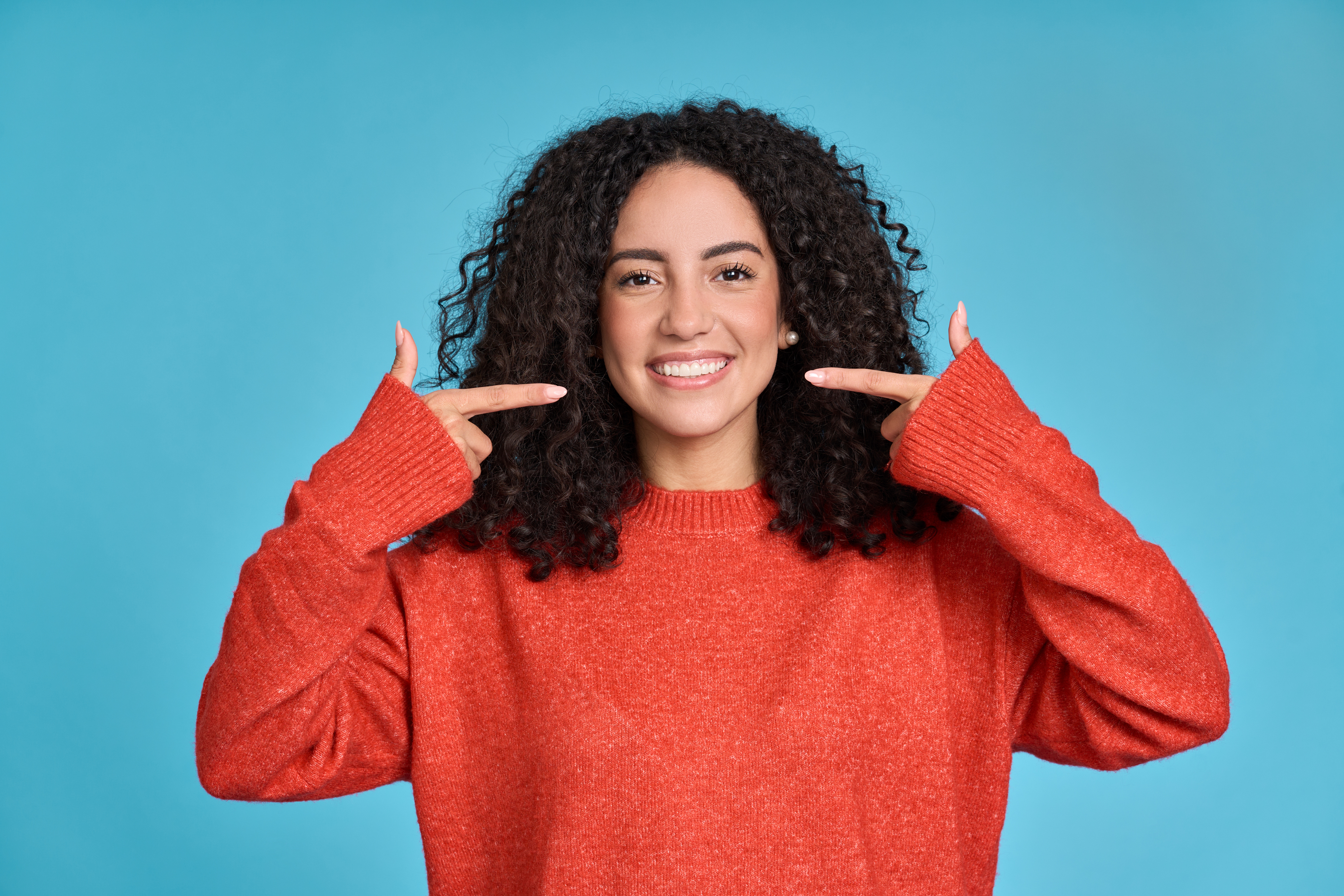 Mujer joven feliz señalando dientes blancos y sanos, mostrando una sonrisa dental perfecta. - Foto de stock de Salud dental libre de derechos