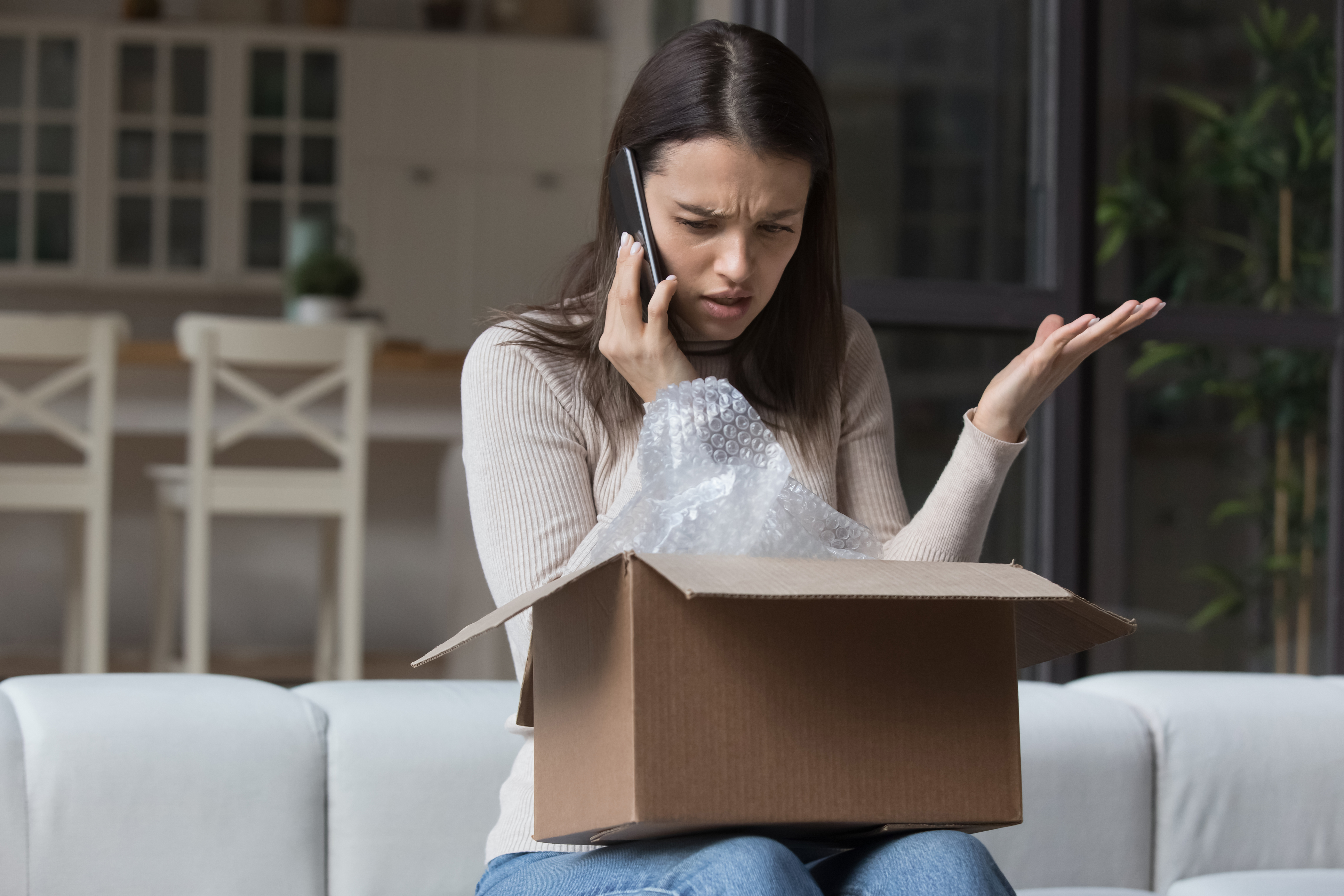 Mujeres expresan quejas a los servicios de soporte a los clientes debido a un paquete dañado - Foto de stock de Quejándose libre de derechos